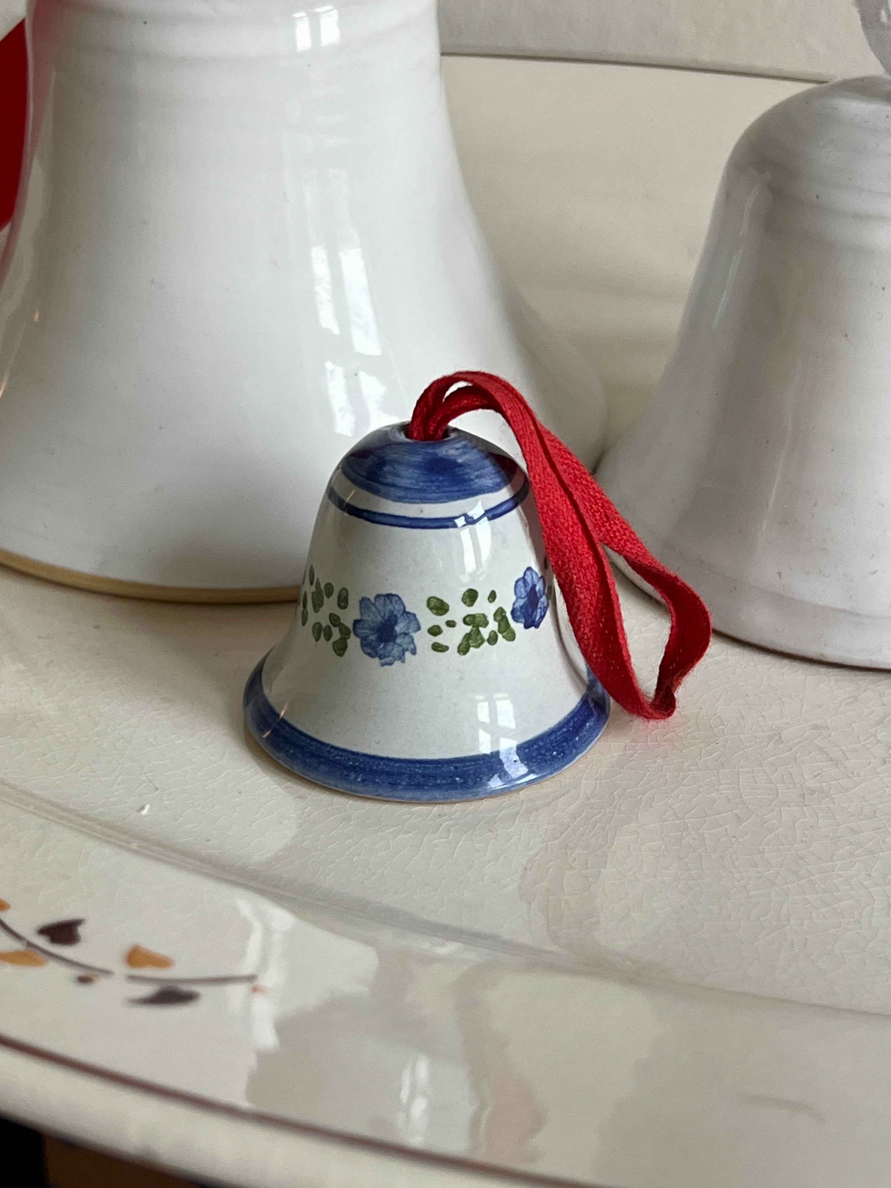 Lille blåmalet porcelænsklokke med rødt bånd